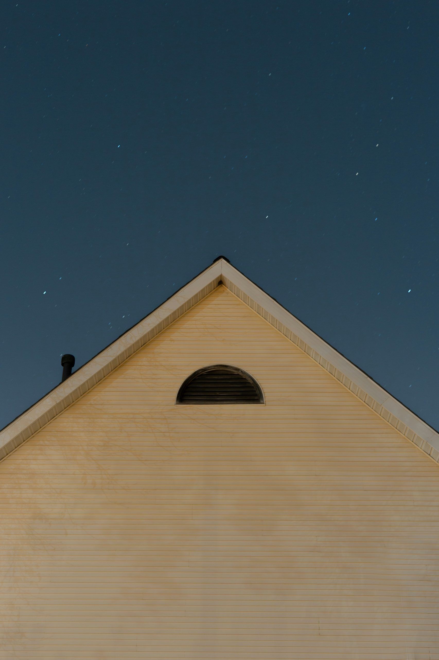 Daylight sky meeting triangular rooftop, symbolizing the angular houses as the foundational intersection of celestial forces and earthly structure in astrological interpretation.
